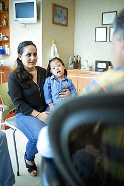 Hispanic mother and daughter with Down Syndrome talking to doctor