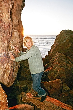 Caucasian man leaning on rocks at ocean