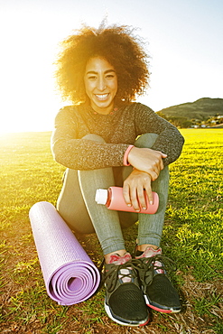 Smiling Hispanic woman sitting in sunny field