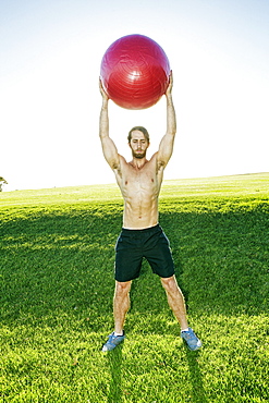 Caucasian man exercising with fitness ball in field