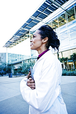 Portrait of smiling Mixed Race doctor holding digital tablet outdoors