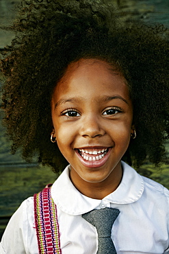 Portrait of smiling Mixed Race girl near wooden wall