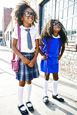 Smiling girls standing on sidewalk ready for school