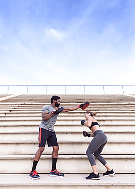 Trainer and woman boxing on bleachers