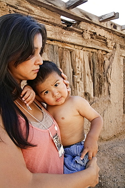 Serious mother holding son outdoors