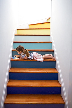 Caucasian girl using digital tablet on multicolor staircase