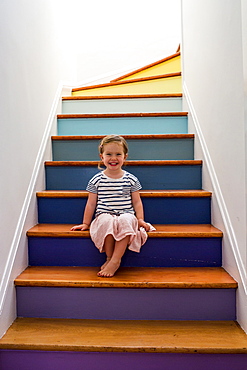 Portrait of smiling Caucasian girl sitting on multicolor staircase