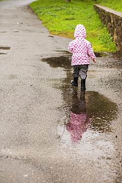 Caucasian girl wearing boots walking in puddle