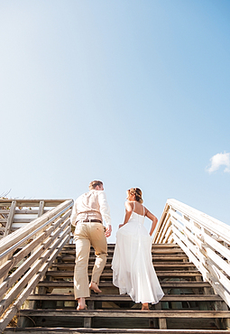 Caucasian bride and groom climbing wooden staircase