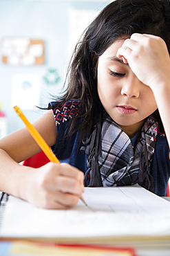 Caucasian girl writing in notebook at school