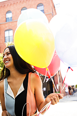 Thai woman holding balloons in city