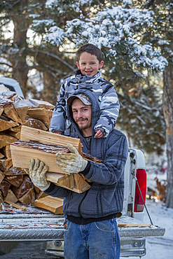 Caucasian father and son carrying firewood from truck