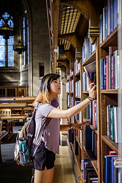 Chinese woman standing in library choosing book