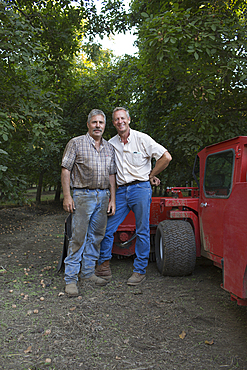 Caucasian men posing near tractor