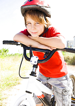 Caucasian boy leaning on bicycle handlebar