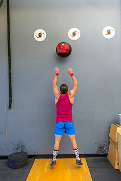 Mixed Race man throwing heavy ball against wall