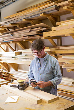 Caucasian carpenter texting on cell phone in workshop