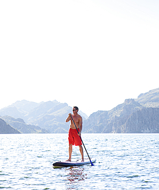 Hispanic man on paddleboard in river