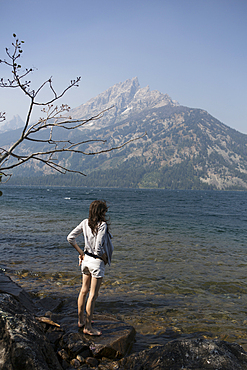 Caucasian woman standing in Jenny Lake admiring Great Teton mountains, Wyoming, United States