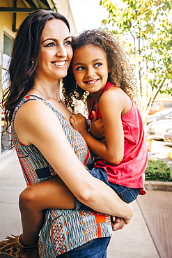 Mother carrying daughter outdoors