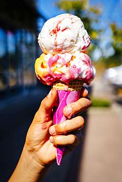 Hand of Mixed Race girl holding melting ice cream cone