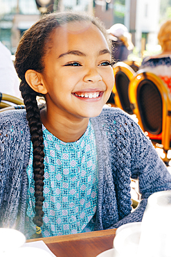 Smiling Mixed Race girl sitting at restaurant table