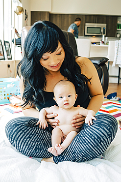 Portrait of mother sitting with baby daughter in lap