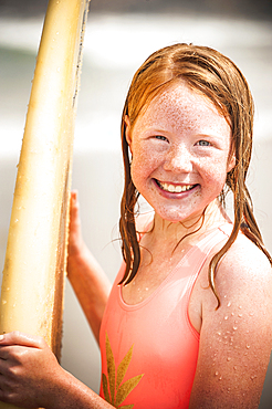 Portrait of smiling girl holding surfboard