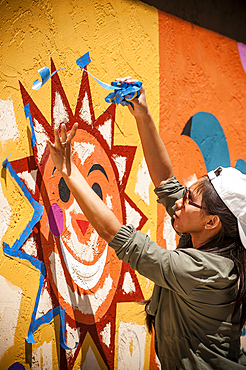 Woman removing painting tape from mural on wall