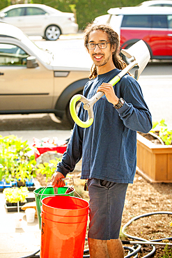 Portrait of smiling Black man holding shovel and buckets