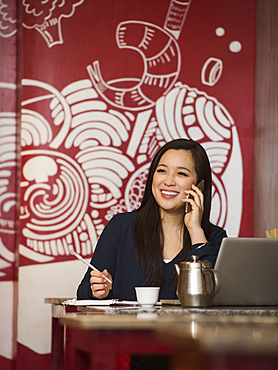 Chinese businesswoman talking on cell phone in restaurant