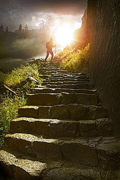 Distant hiker on stone staircase at sunset