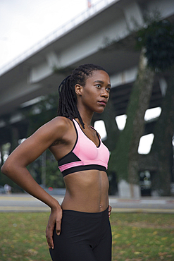 Serious Mixed Race woman wearing pink sports-bra near bridge