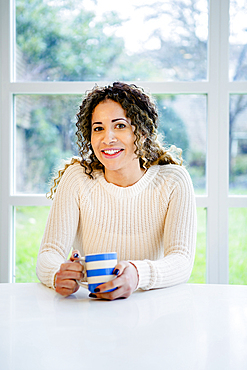 Smiling woman sitting at table holding coffee cup