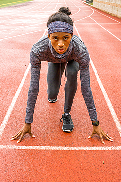 Black woman waiting at starting line on track