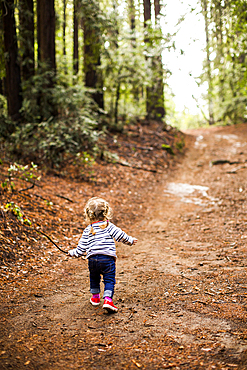 Caucasian girl walking on forest path