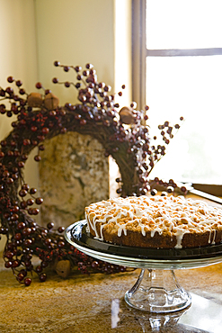 Glass platter holding coffee cake on counter near window