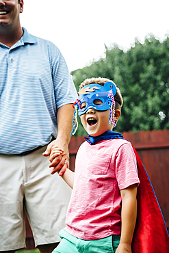 Caucasian father and superhero son holding hands