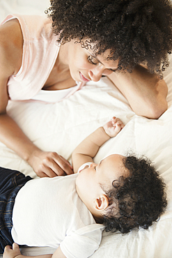 Mother watching baby son sleeping on bed