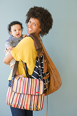 Mother carrying three bags and baby son