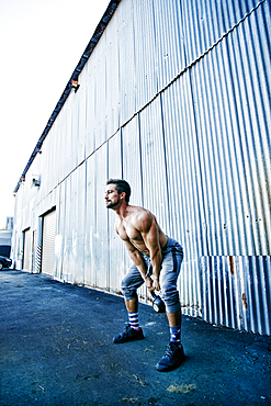 Caucasian man lifting kettlebell outdoors