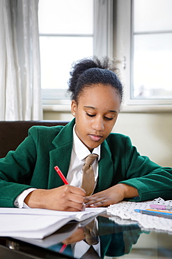 Black girl wearing school uniform doing homework