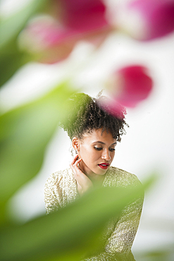 Pensive glamorous Black woman behind flowers