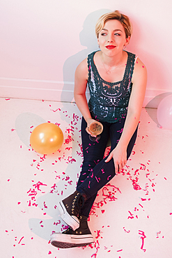 Caucasian woman sitting on floor at party covered in confetti