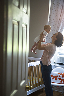 Caucasian mother holding baby son face to face in bedroom