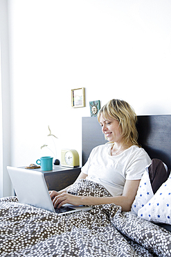 Caucasian woman using laptop in bed