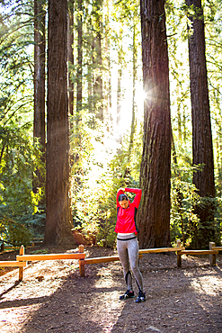 Serious woman stretching arm on forest path