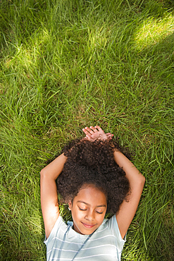 Smiling Hispanic girl laying in grass