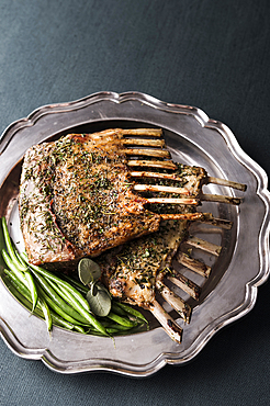 Rack of lamb and green beans on silver platter