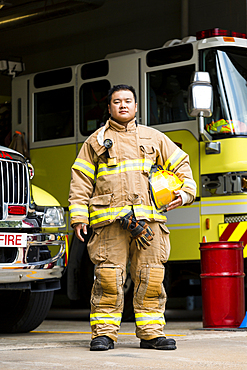 Serious Chinese fireman posing near fire trucks